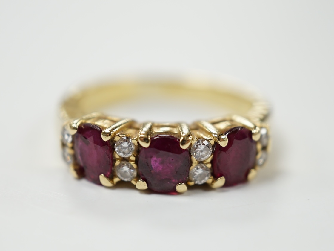 A modern yellow metal and three stone ruby set half hoop ring, with diamond chip spacers, size L, gross weight 5 grams. Condition - fair